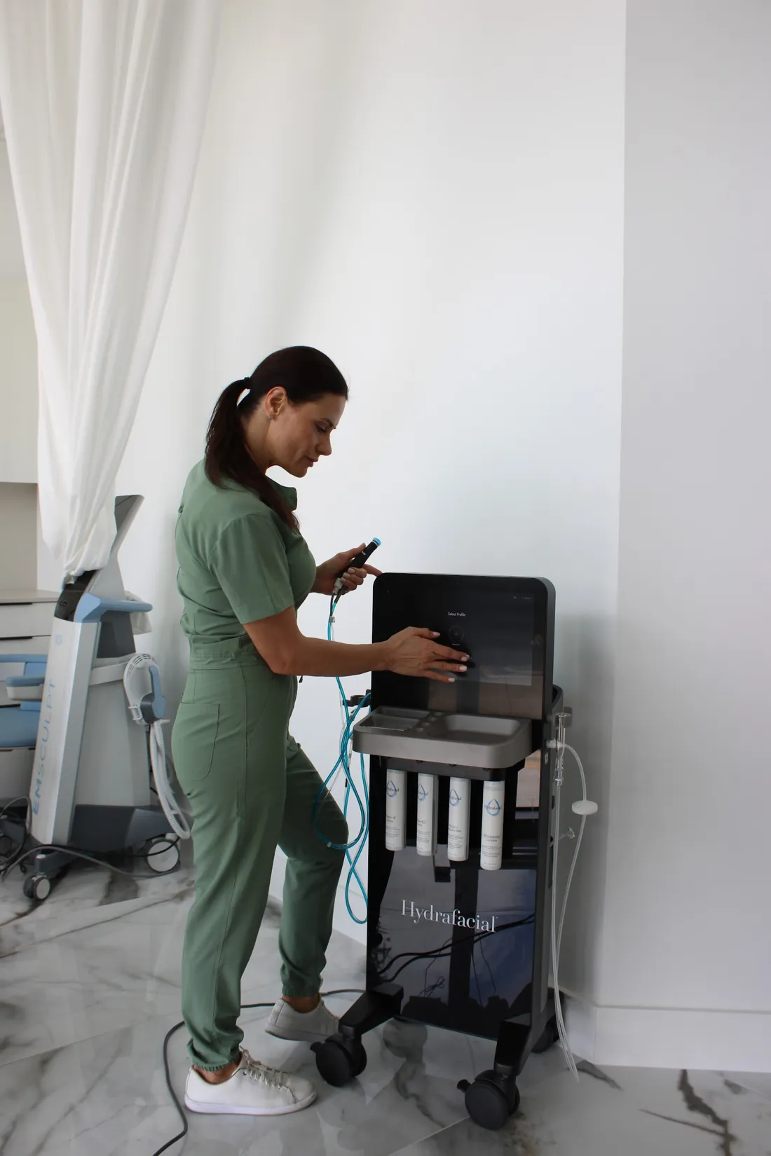 A WO/MAN specialist preparing the HydraFacial in a private treatment room with white curtains